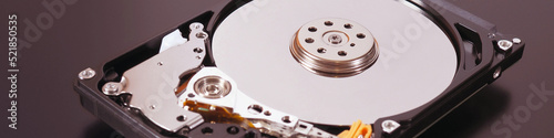 A disassembled open hard disk drive HDD of computer or laptop lies on brown matte surface. IT close-up. Banner about computer hardware and equipment. Data storage headline. Macro
