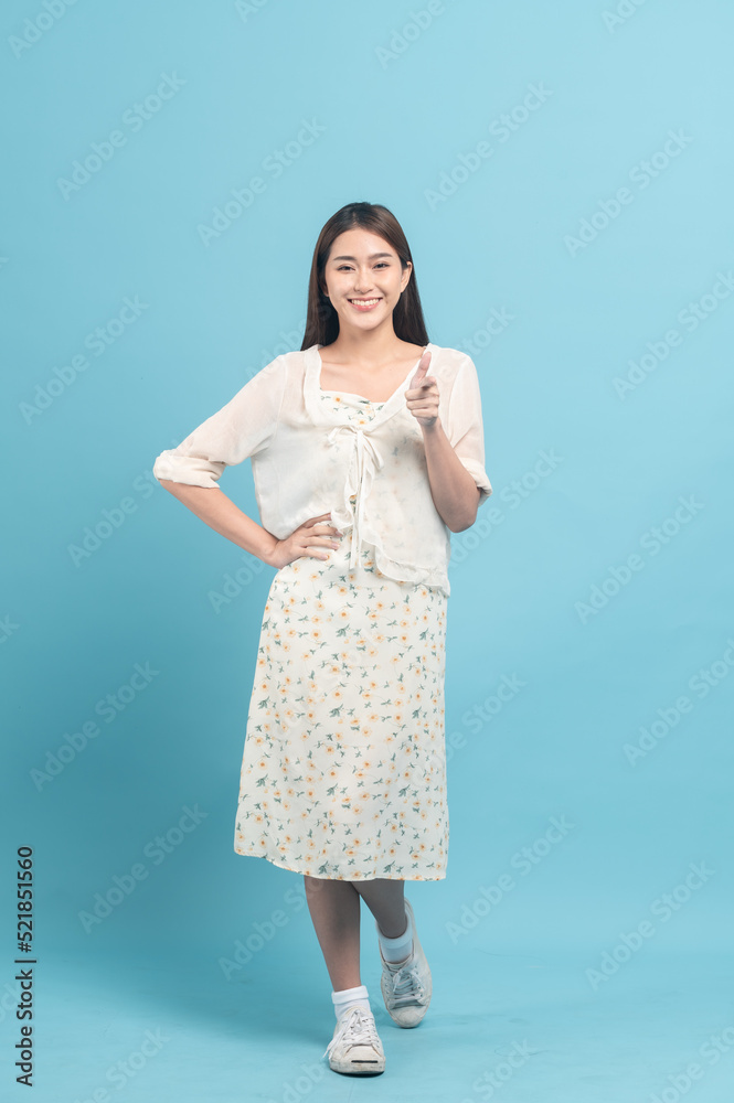 Beautiful young asian woman in white dress with flower pattern isolated on blue background Beautiful young asian woman in white dress with flower pattern isolated on blue background