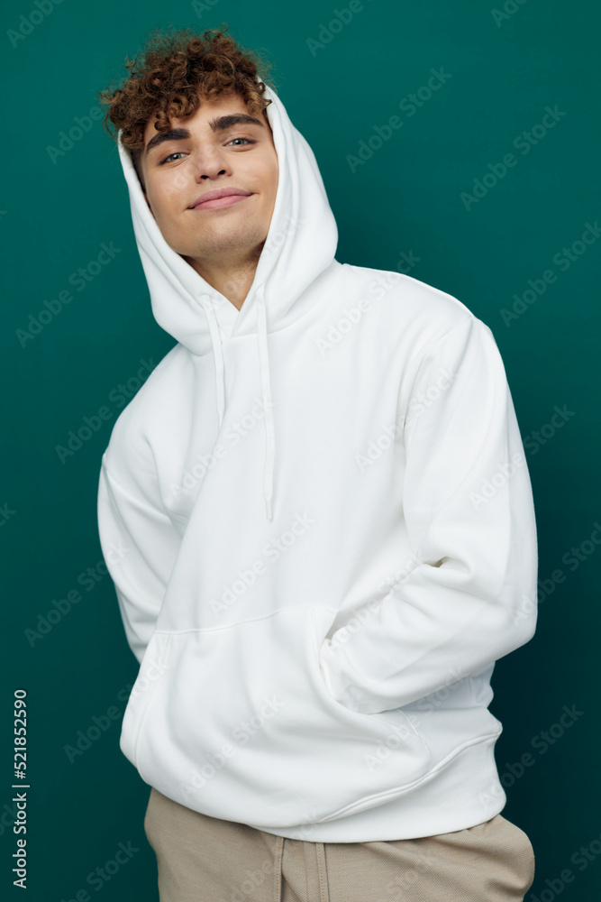 a handsome man stands on a green background in a white hoodie with a hood on his head and keeps his hands in the pocket of the hoodie a handsome man stands on a green background in a white hoodie with a hood on his head and keeps his hands in the pocket of the hoodie