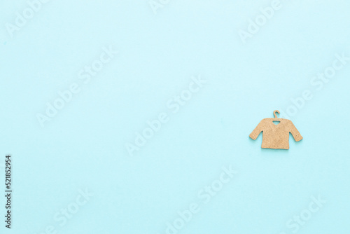 A wooden figure of a clothes hanger on a blue background. Shopping concept