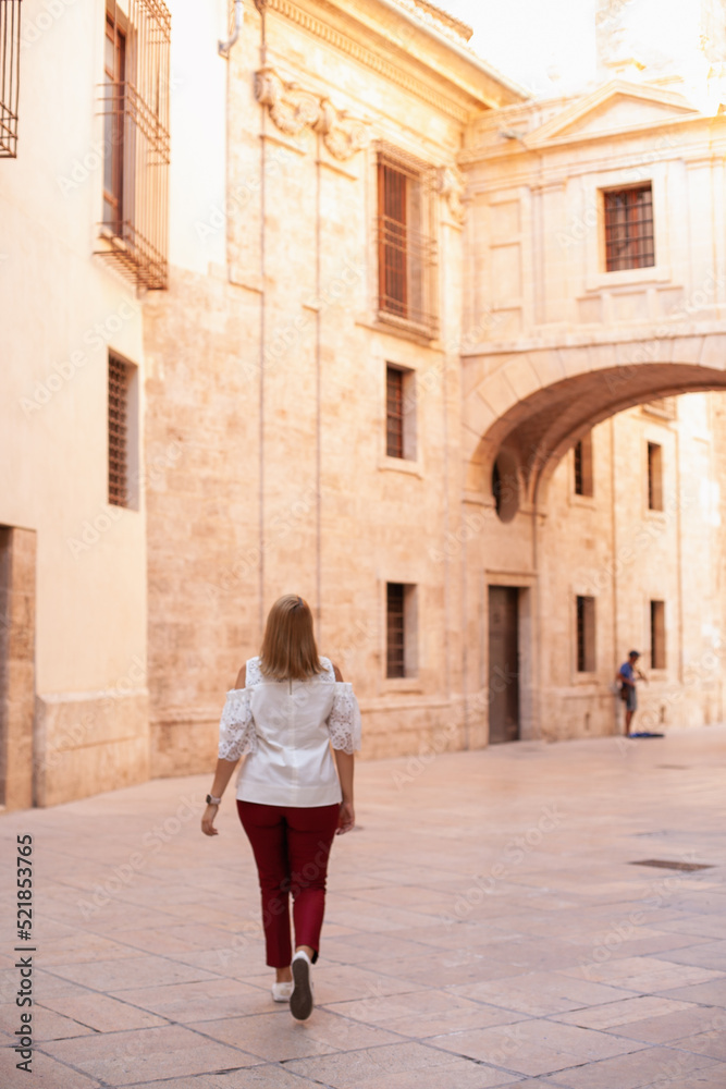 Rear view on woman walking in the historic center. Tourism in Europe