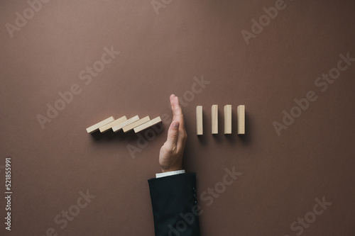 Hand of a businessman stopping falling dominos