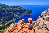 Girl traveler sitting on hill rock over blue sea bay in Turkey, butterfly valley. Enjoy holiday vacation and beautiful traveling places