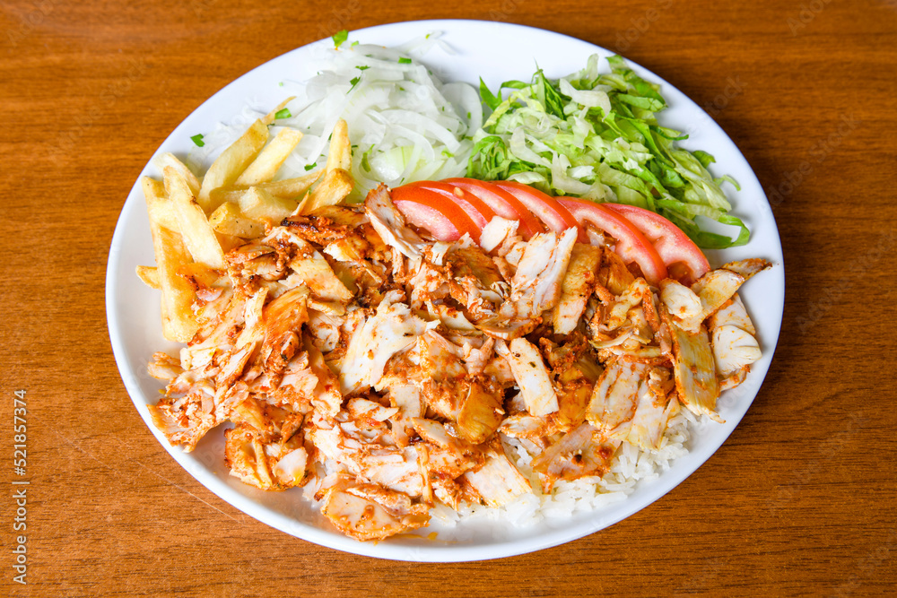 Turkish and Arabic Traditional Ramadan doner kebab with tasty tomato sauce and rice or turkish pilav in white plate on wood table background. ( Pilav ustu doner) Turkish and Arabic Traditional Ramadan doner kebab with tasty tomato sauce and rice or turkish pilav in white plate on wood table background. ( Pilav ustu doner)