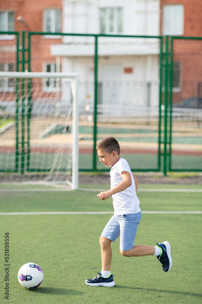 A boy plays football in the school yard