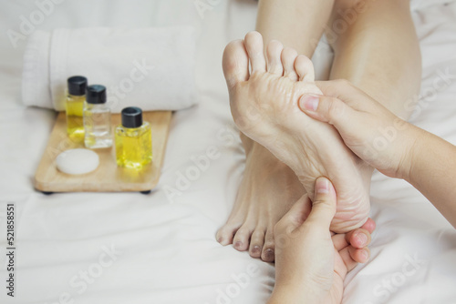 Hands of a professional foot massager with oils and health care products on white bed. Concept of health care, relaxation, foot spa treatment. or product introduction for women's foot spa