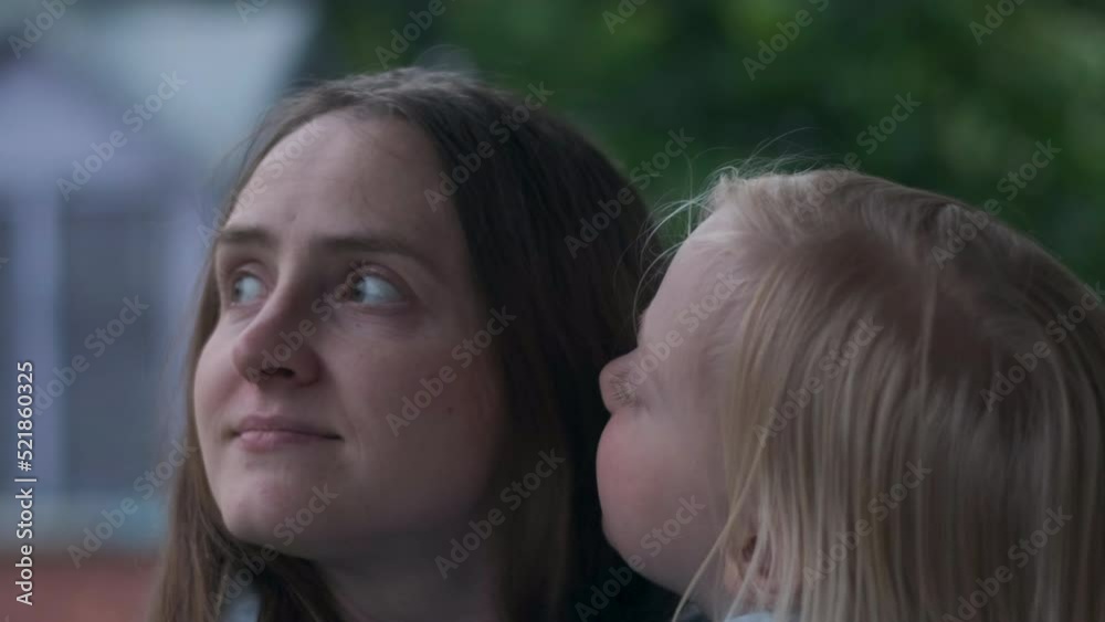 Young mother with small blonde girl smiles and enjoys time spent together. Daughter kisses happy mom Young mother with small blonde girl smiles and enjoys time spent together. Daughter kisses happy mom