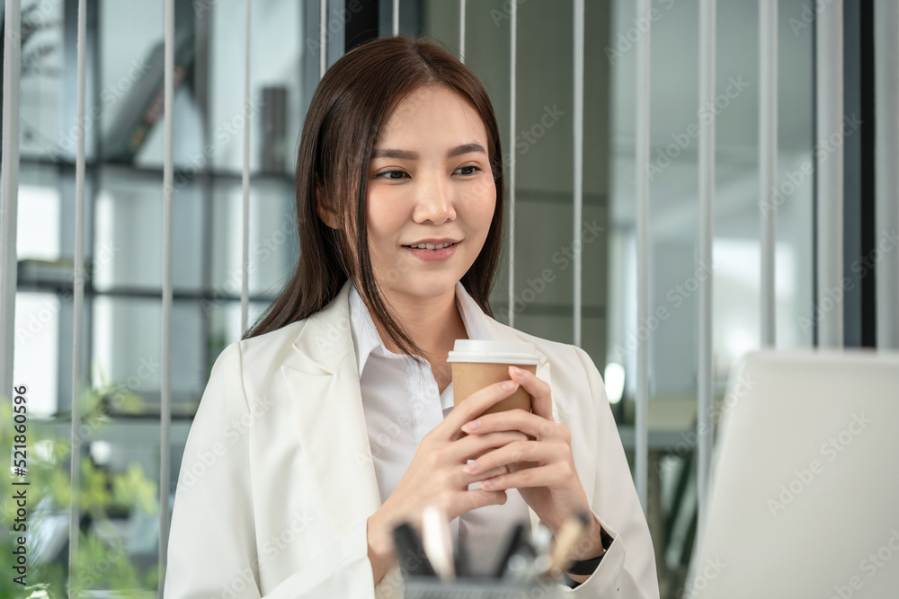 Asian businesswoman analyzing documents (data graph) and sipping coffee while working in a private office, Happy working lifestyle, Modern private office Asian businesswoman analyzing documents (data graph) and sipping coffee while working in a private office, Happy working lifestyle, Modern private office
