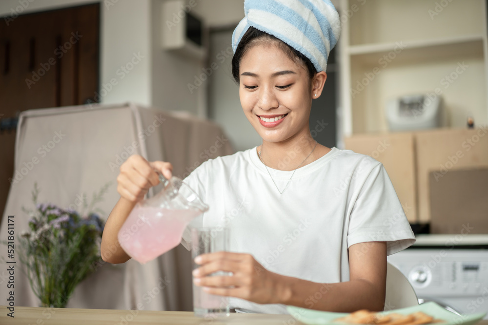 Half Asian woman drinking juice and eating crackers (Healthy whole grain) for breakfast before going to work, Small room in condominium background, Wake-up activities Half Asian woman drinking juice and eating crackers (Healthy whole grain) for breakfast before going to work, Small room in condominium background, Wake-up activities