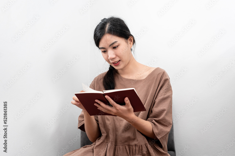 Beautiful woman is reading a book or literature while sitting to relaxation on carpet in the living Beautiful woman is reading a book or literature while sitting to relaxation on carpet in the living