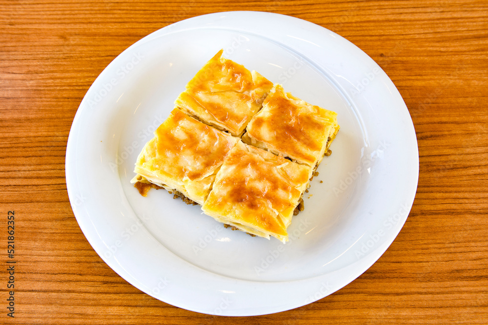 Turkish style meat stuffed filo dough borek served kol boregi. Cheese and minced pie are sliced on a marble background. Turkish name: Kol Boregi, kiymali, peynirli su boregi. Turkish style meat stuffed filo dough borek served kol boregi. Cheese and minced pie are sliced on a marble background. Turkish name: Kol Boregi, kiymali, peynirli su boregi.