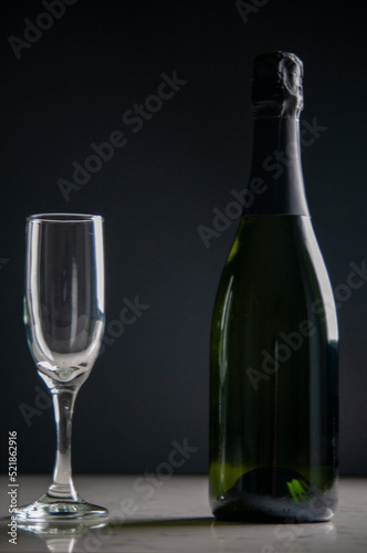 Bottle of champagne and a glass on a dark background
