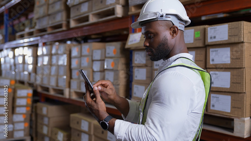 Business concept of 4k Resolution. African man checking goods in warehouse. Data collection of imported products from abroad.