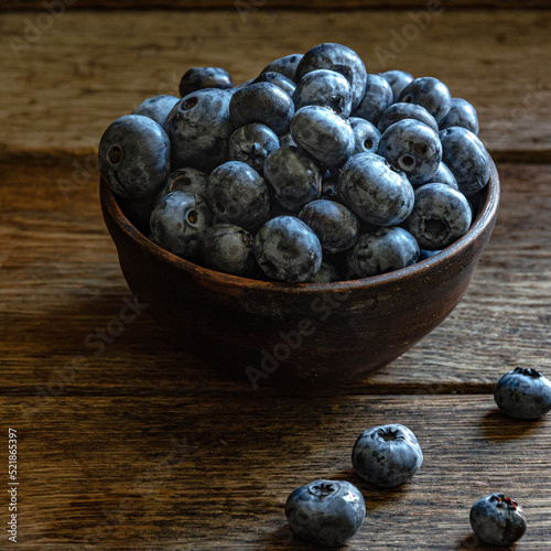 Blueberries in a clay cup, on a wooden table. Ripe berries in the kitchen, harvest.