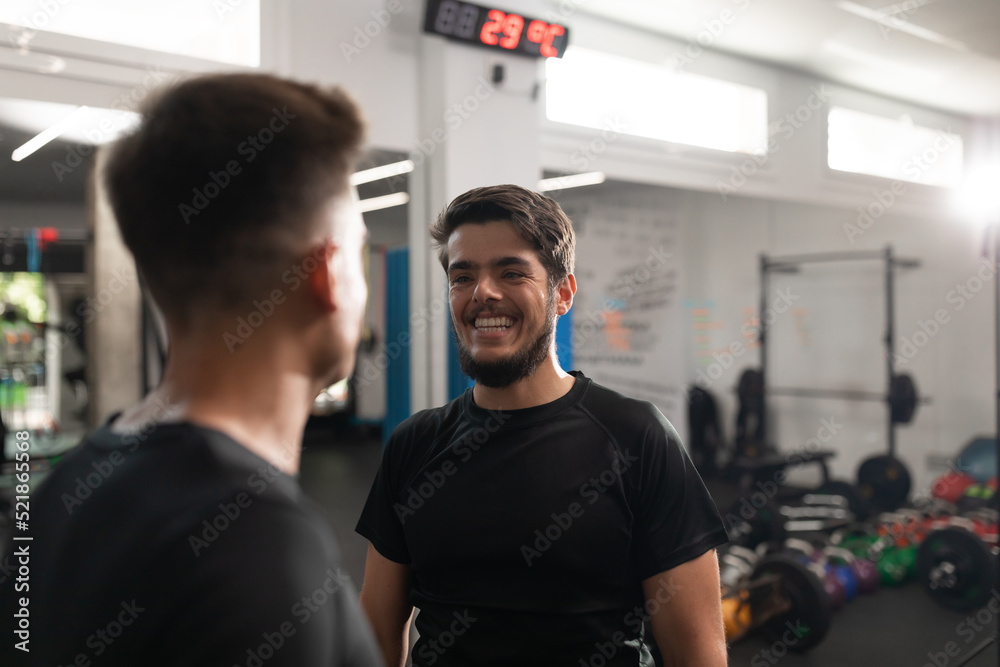 Two personal trainers smiling at each other at their workplace in the crossfit box Two personal trainers smiling at each other at their workplace in the crossfit box