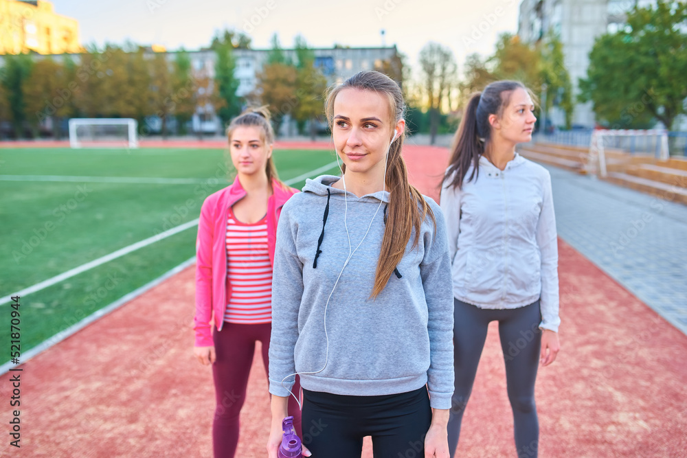 Three girls doing stretching exercises at the stadium Three girls doing stretching exercises at the stadium