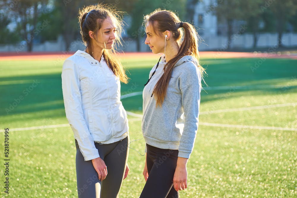 Two girls in sportswear posing at the stadium.Portrait of two sports girlfriends at the sports stadium.