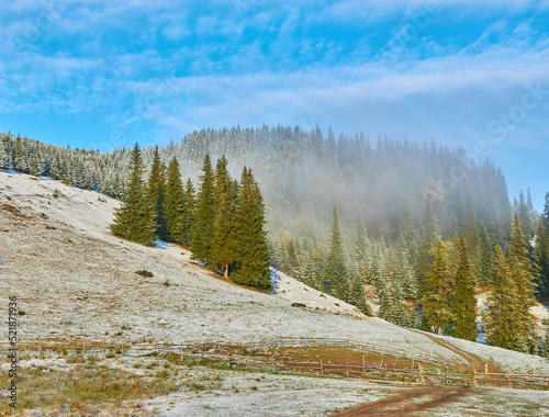 Amazing scene on autumn mountains. First snow and orange trees in fantastic morning fog. Carpathians, Europe.