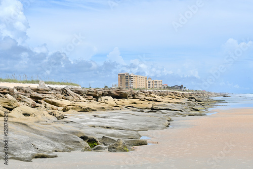 Coquina rocks on the beach with condo near Washington Oaks Gardens State Park, Palm Coast, Florida between St Augustine and Flagler Beach.