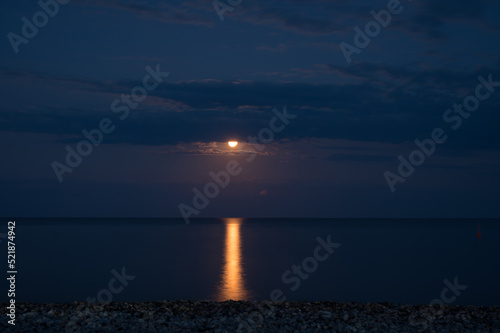 Night landscape. Full moon over the sea. Reflection of the moon path.