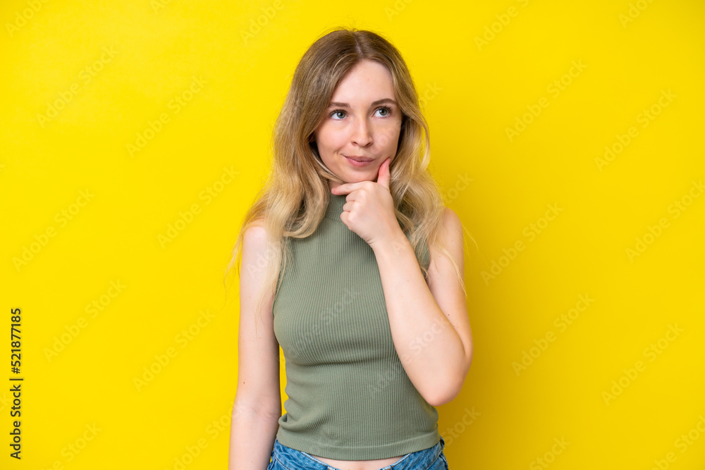 Blonde English young girl isolated on yellow background thinking an idea while looking up Blonde English young girl isolated on yellow background thinking an idea while looking up