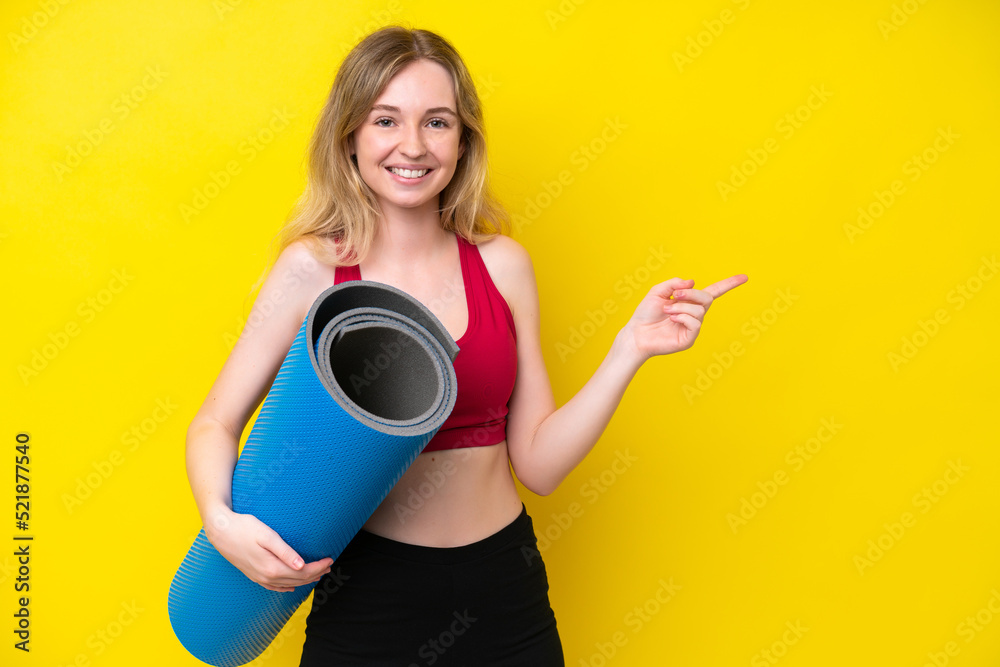 Young sport caucasian woman going to yoga classes while holding a mat isolated on yellow background pointing finger to the side Young sport caucasian woman going to yoga classes while holding a mat isolated on yellow background pointing finger to the side