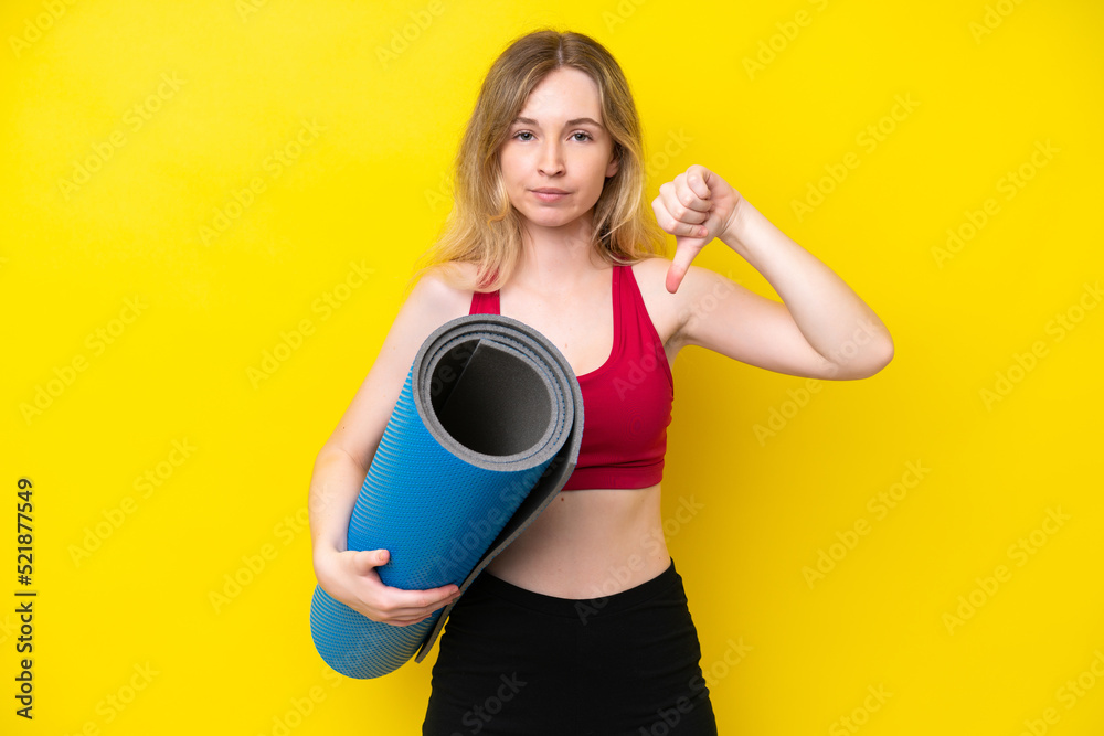 Young sport caucasian woman going to yoga classes while holding a mat isolated on yellow background showing thumb down with negative expression Young sport caucasian woman going to yoga classes while holding a mat isolated on yellow background showing thumb down with negative expression