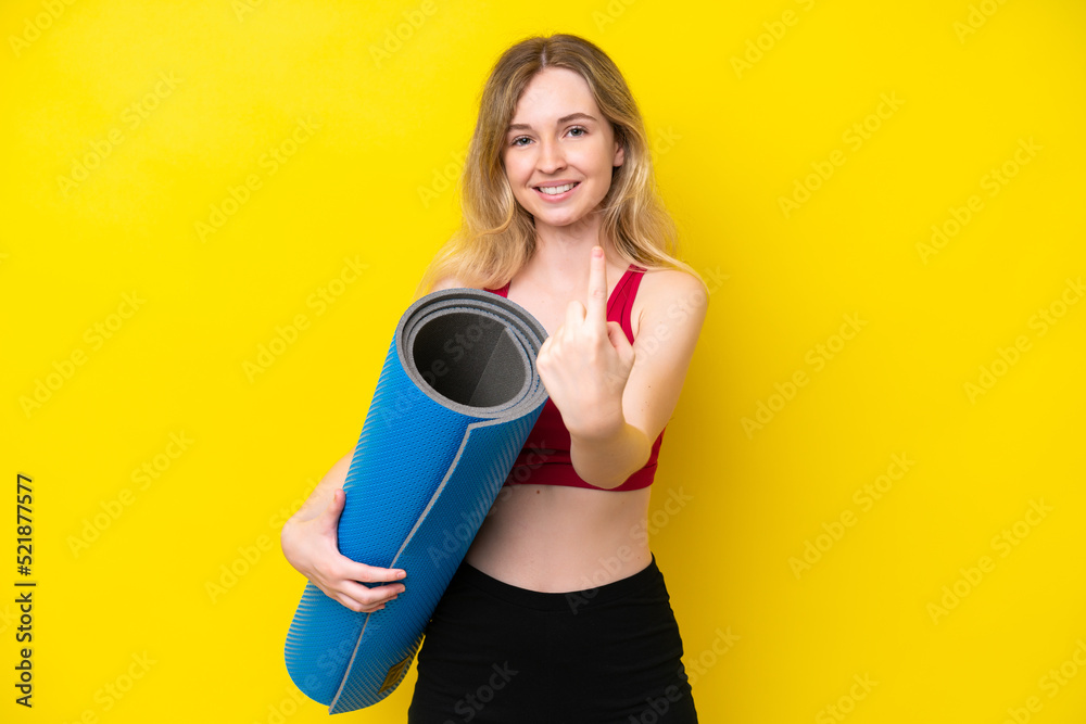 Young sport caucasian woman going to yoga classes while holding a mat isolated on yellow background doing coming gesture Young sport caucasian woman going to yoga classes while holding a mat isolated on yellow background doing coming gesture