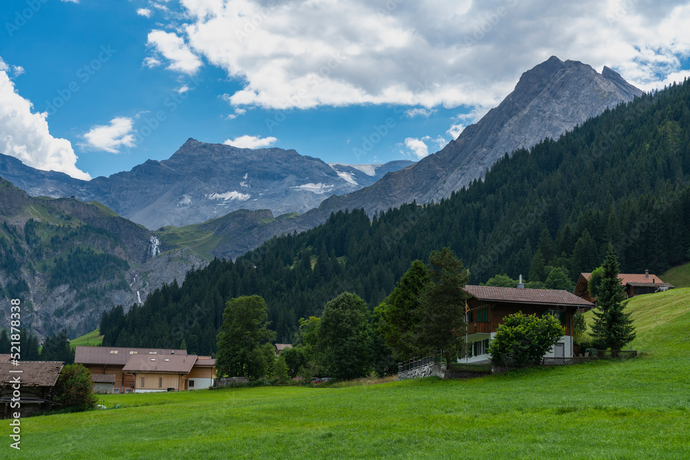 alte Bauernhäuser aus Holz im Boden, Adelboden. Streusiedlung mit Wiesen und Wäldern in den schweizer Alpen. Berge im Hintergrund