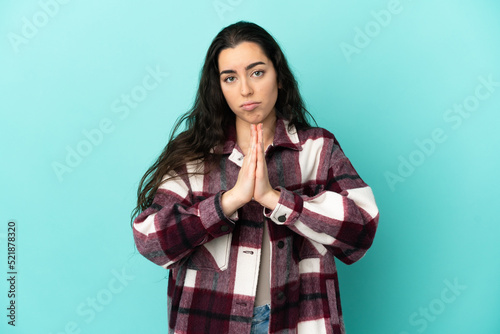Young caucasian woman isolated on blue background keeps palm together. Person asks for something