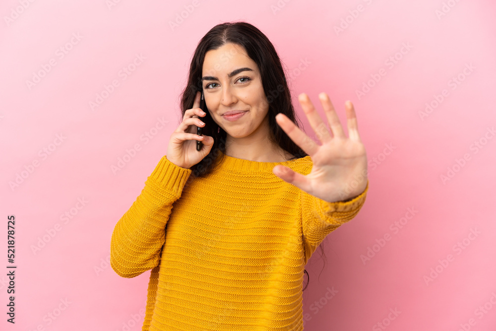 Young caucasian woman using mobile phone isolated on pink background counting five with fingers Young caucasian woman using mobile phone isolated on pink background counting five with fingers