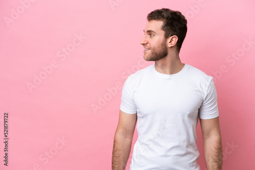 Young caucasian man isolated on pink background looking side