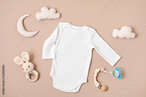 Flat lay with baby sleep accessories with pacifier, pajamas and toys. Newborn sleeping rules concept. Onesie mockup photo