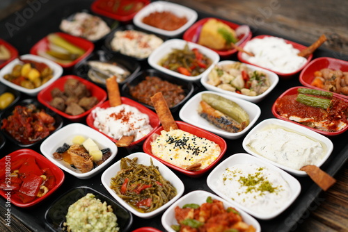 Turkish and Greek appetizers (meze) table. Traditional Turkish cuisine cold appetizers. Different types of appetizers in colorful special plates. Olives, hummus, yogurt, pickles, etc. Selective focus
