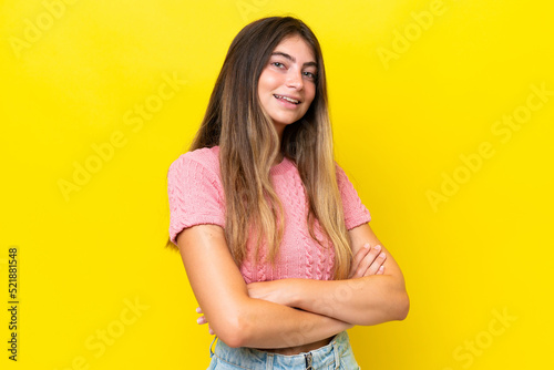 Young caucasian woman isolated on yellow background with arms crossed and looking forward