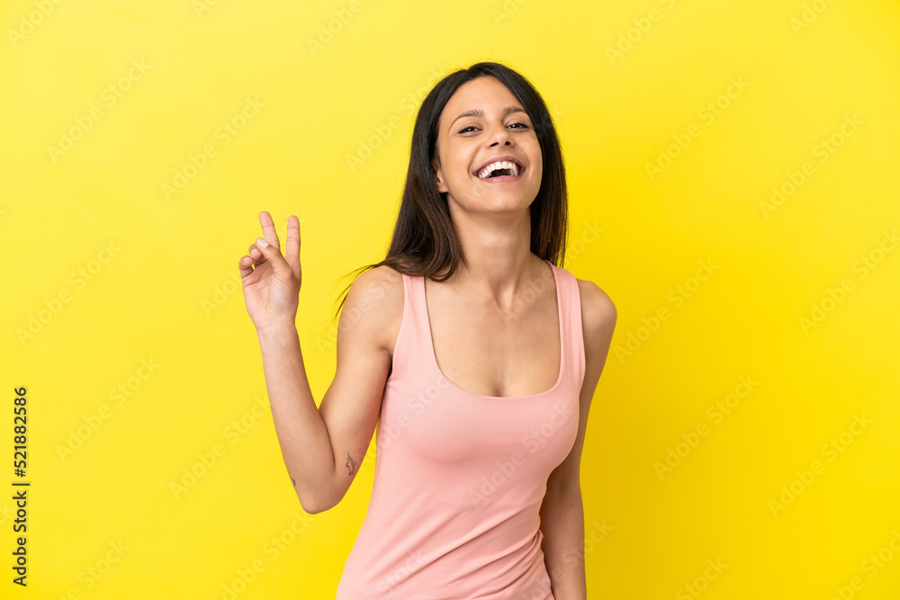 Young caucasian woman isolated on yellow background smiling and showing victory sign Young caucasian woman isolated on yellow background smiling and showing victory sign