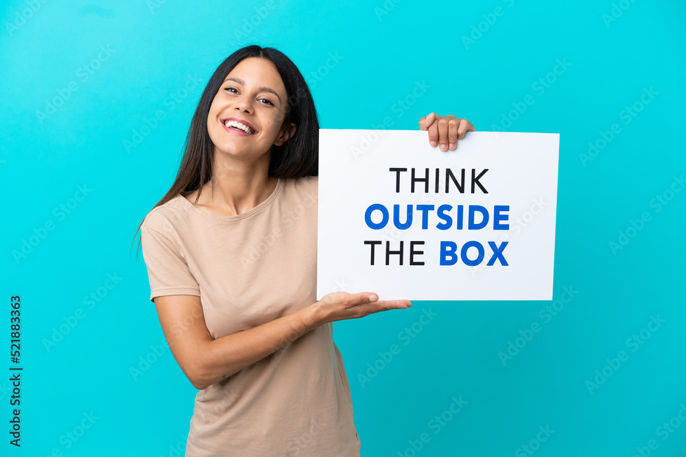 Young woman over isolated background holding a placard with text Think Outside The Box with happy expression Young woman over isolated background holding a placard with text Think Outside The Box with happy expression
