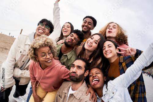 Big group of cheerful young friends taking selfie portrait fool around. Happy people having fun. Concept of community, youth lifestyle and friendship photo