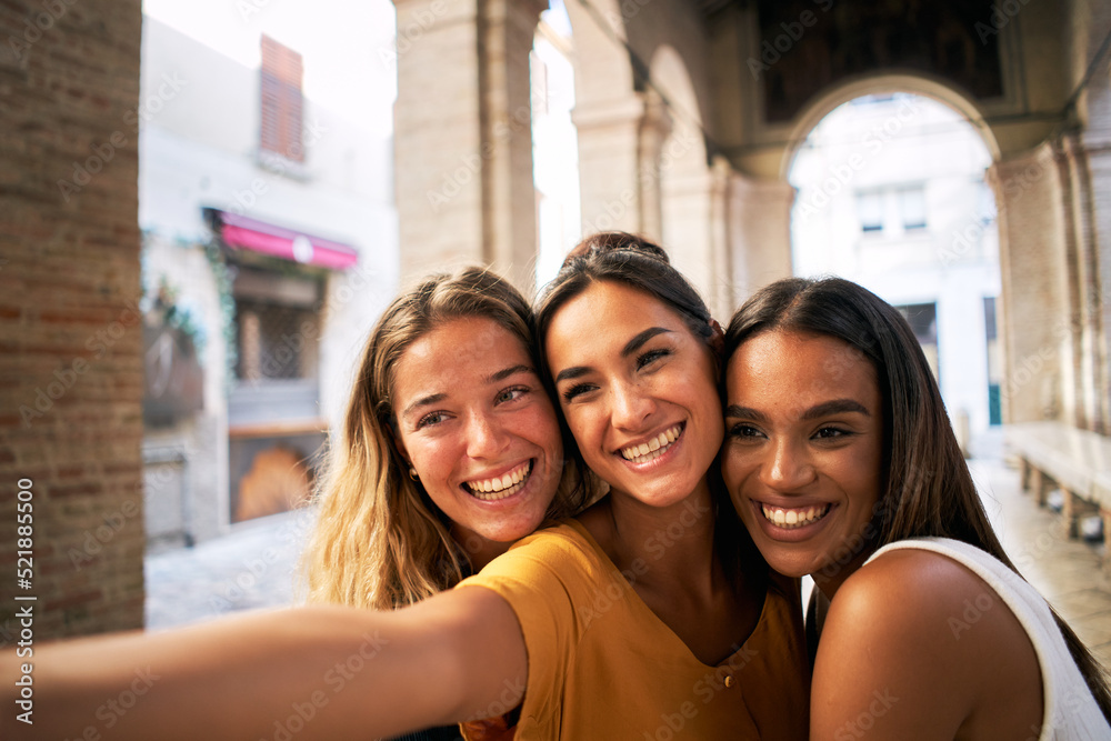 Fototapeta premium three happy female friends having fun together and taking smiling selfie