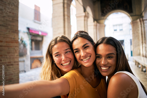 three happy female friends having fun together and taking smiling selfie