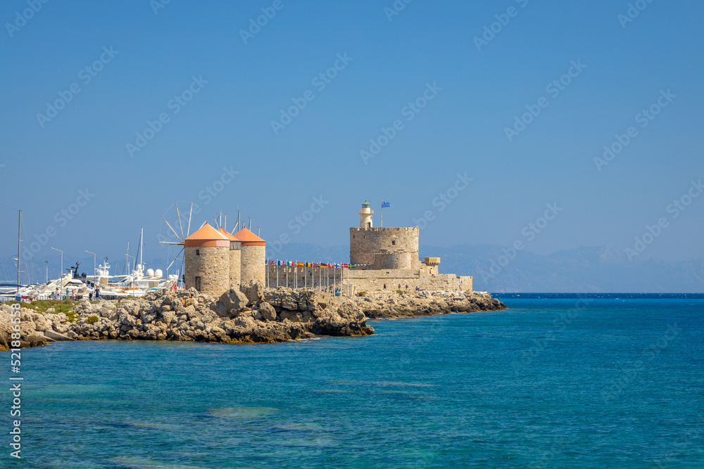 Windmills of Mandraki harbour and Saint Nicholas Fortress in Rhodes town, Greece, Europe.