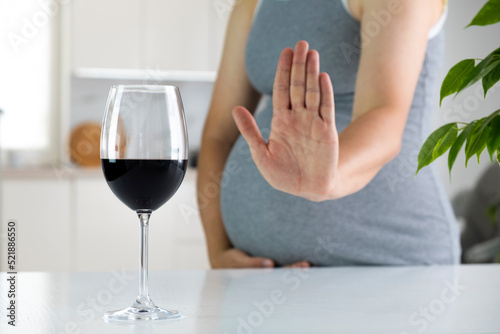 Fototapeta Pregnant woman show NO gesture to glass of wine