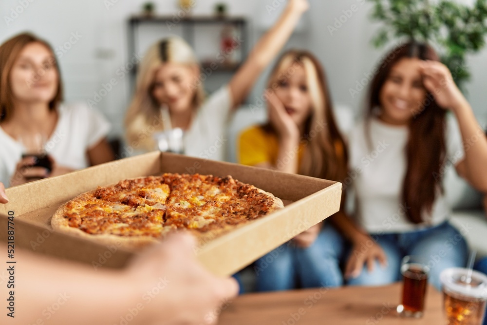 Group of young friends woman surprise for italian pizza sitting on the sofa at home.
