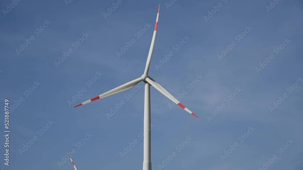 Propeller of wind turbine turning slowly against clear blue sky