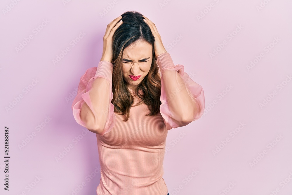 Young hispanic girl wearing casual clothes suffering from headache desperate and stressed because pain and migraine. hands on head.