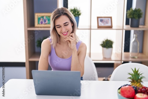 Young woman using laptop sitting on table at home