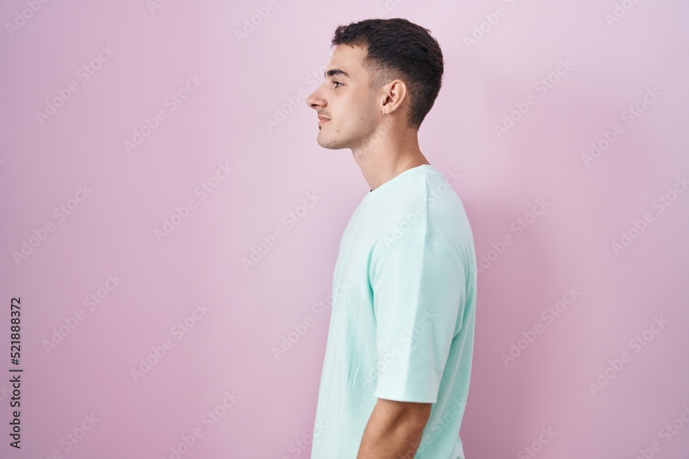 Handsome hispanic man standing over pink background looking to side, relax profile pose with natural face and confident smile. Handsome hispanic man standing over pink background looking to side, relax profile pose with natural face and confident smile.