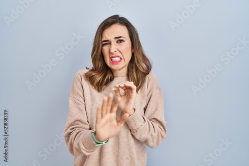 Young woman standing over isolated background disgusted expression, displeased and fearful doing disgust face because aversion reaction.