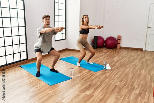 Young hispanic sporty couple concentrate training legs exercise at the sport center.