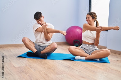 Young man and woman couple smiling confident stretching at sport center